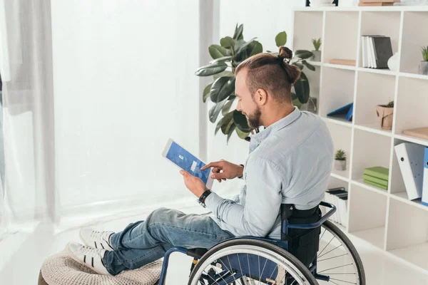 Человек на инвалидной коляске с помощью планшета — стоковое фото