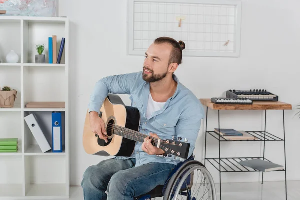 Человек на инвалидной коляске играет на гитаре — стоковое фото