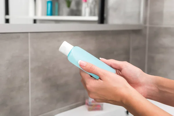 Woman holding bottle of lotion — Stock Photo