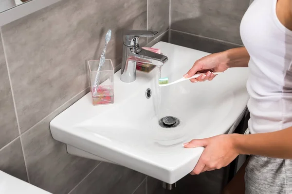 Girl putting toothbrush under water — Stock Photo