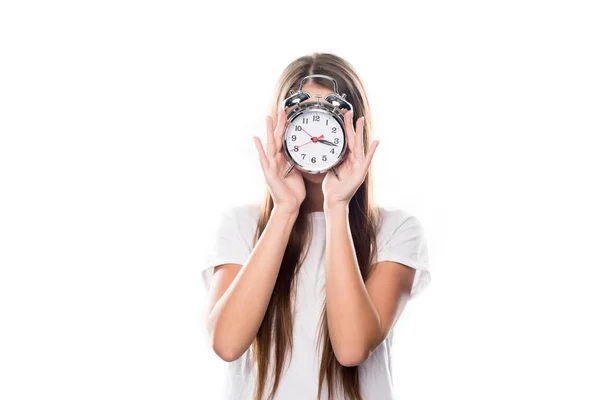 Chica cubriendo la cara con despertador - foto de stock