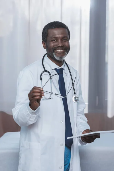 Doctor holding eyeglasses and tablet — Stock Photo