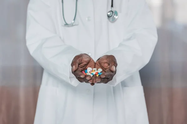 Doctor holding colored pills — Stock Photo