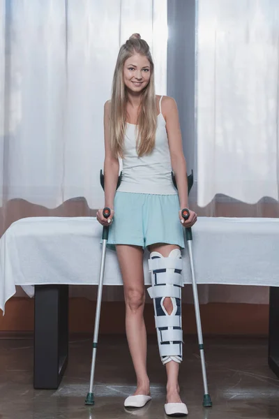 Chica con muletas y soporte para las piernas - foto de stock