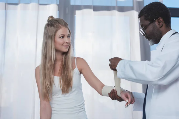 Doctor bandaging patient hand — Stock Photo