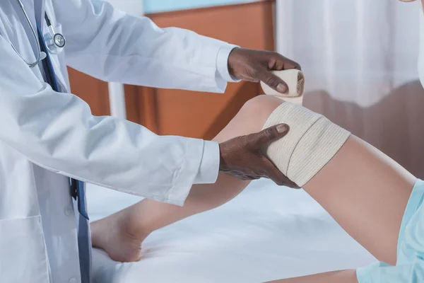 Doctor putting on elastic bandage — Stock Photo