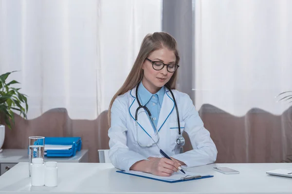 Doctor writing something on clipboard — Stock Photo