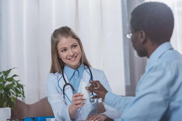 Doctor giving plastic jar with pills — Stock Photo