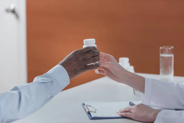 Doctor dando frasco de plástico con pastillas - foto de stock