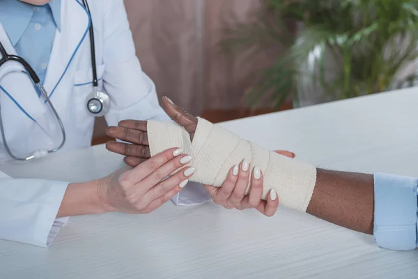 Doctor bandaging patient hand — Stock Photo