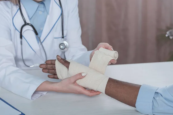 Doctor bandaging patient hand — Stock Photo