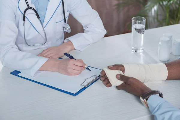 Doctor sitting at table with patient — Stock Photo