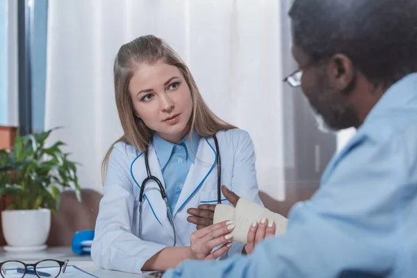 Doctor tocando paciente mano lesionada - foto de stock