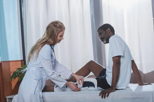 Doctor putting on leg brace — Stock Photo