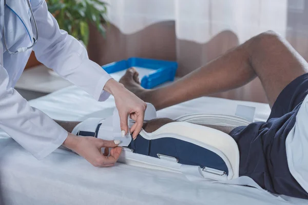 Doctor poniéndose un corsé para las piernas - foto de stock