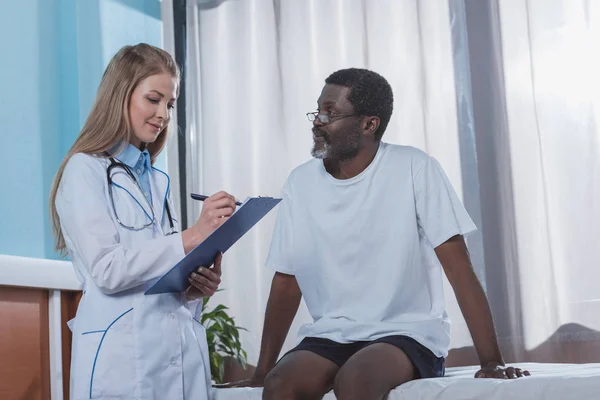 Doctor writing down something to clipboard — Stock Photo