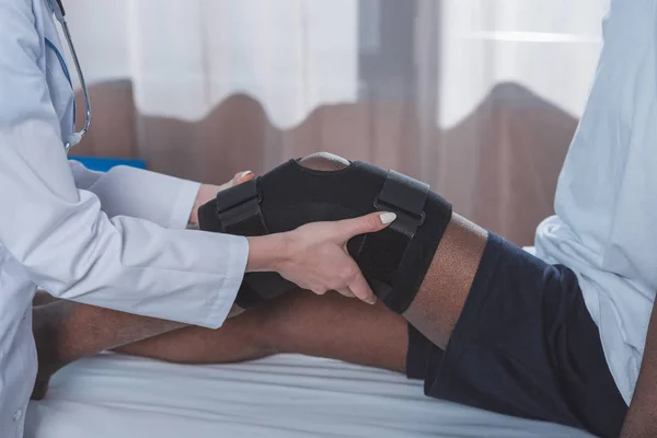 Doctor putting on knee brace — Stock Photo