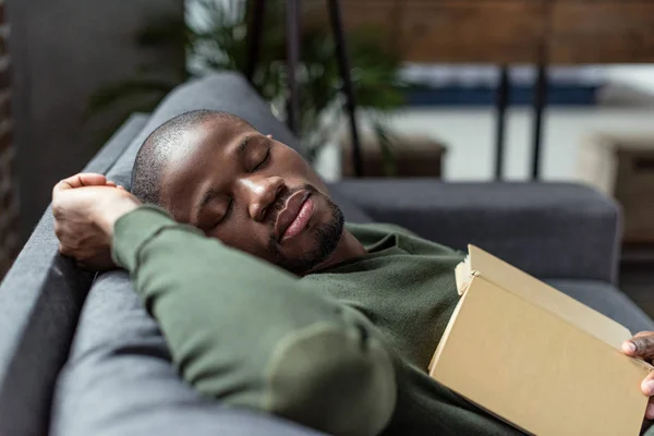 Africano americano hombre durmiendo en sofá - foto de stock