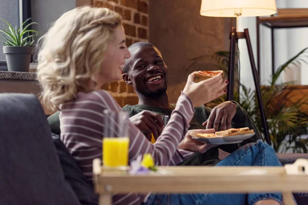 Selective focus of happy woman feeding african american boyfriend with toast during breakfast at home — Stock Photo