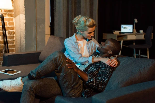 Young multicultural couple resting on sofa together at home — Stock Photo