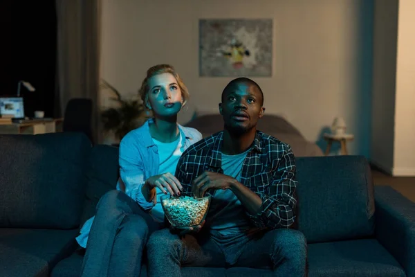 Portrait de jeunes couples multiethniques regardant un film ensemble sur un canapé à la maison — Photo de stock