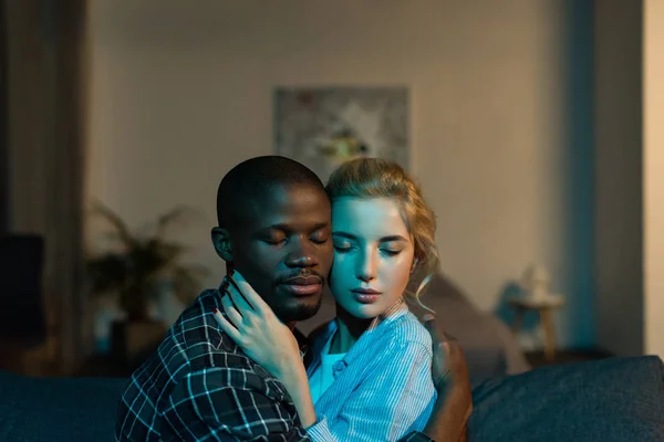 Portrait of multicultural couple with eyes closed hugging each other at home — Stock Photo