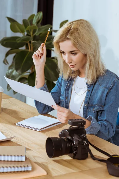 Retrato de jovem fotógrafo olhando para amostras de fotos no local de trabalho no escritório — Fotografia de Stock