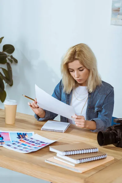 Portrait of concentrated photographer looking at photoshoot samples at workplace in office — Stock Photo