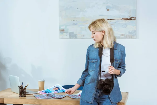 Portrait of focused photographer looking at photoshoot samples at workplace in office — Stock Photo