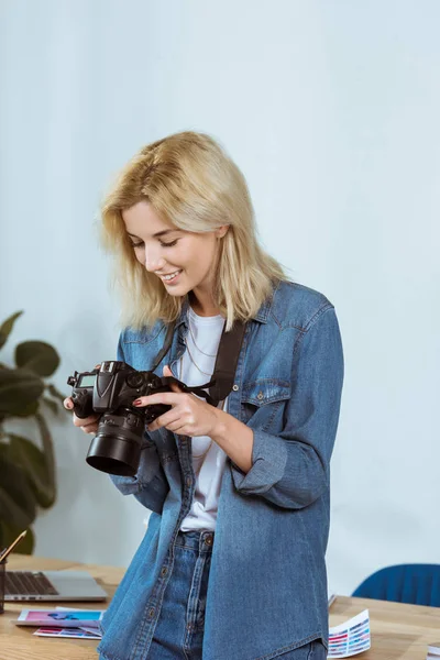 Portrait of cheerful photographer looking at photo camera screen in hands in studio — Stock Photo