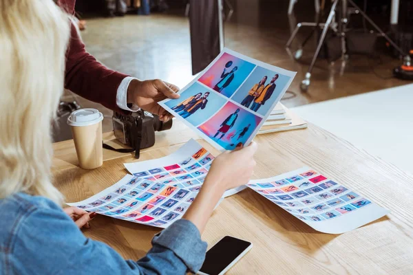 Cropped shot of multicultural photographers choosing photos together at workplace in office — Stock Photo