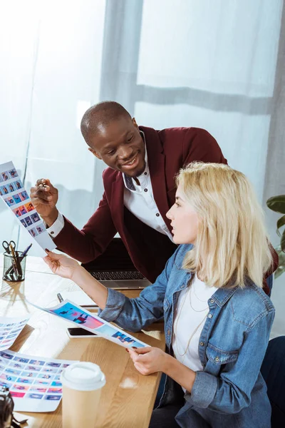 Side view of multicultural photographers choosing portfolio together at workplace in office — Stock Photo