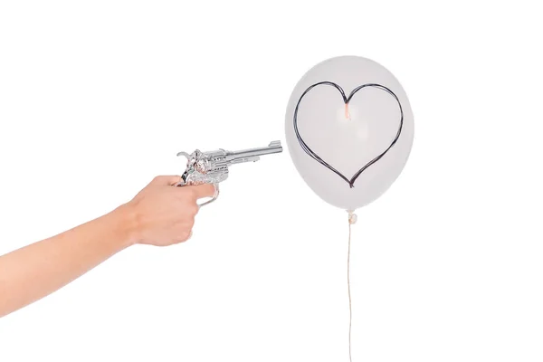 Hand with revolver and balloon with heart — Stock Photo