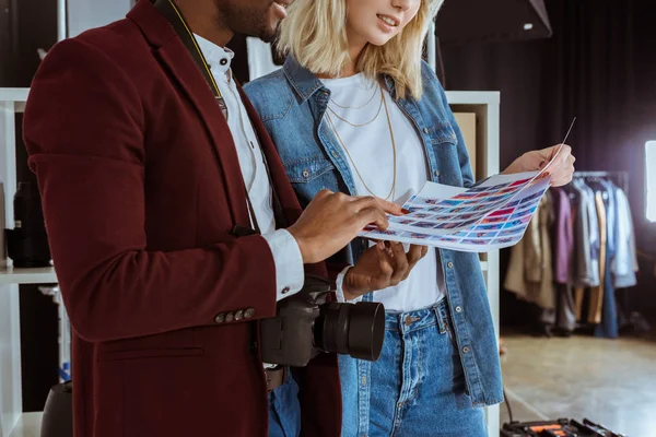 Cropped shot of multiethnic photographers looking at portfolio together in studio — Stock Photo