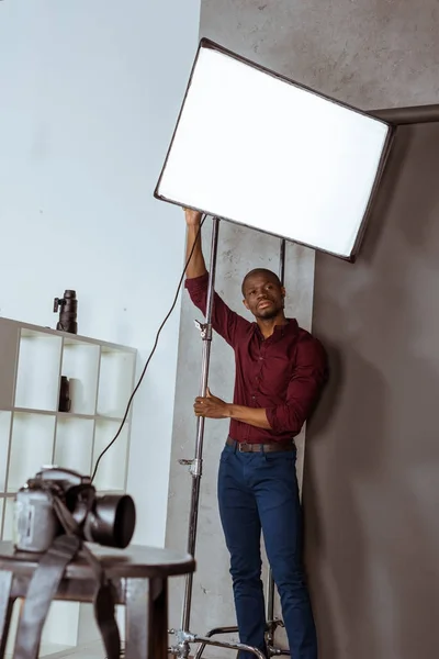 Fotografo afroamericano si prepara per il servizio fotografico in studio — Foto stock