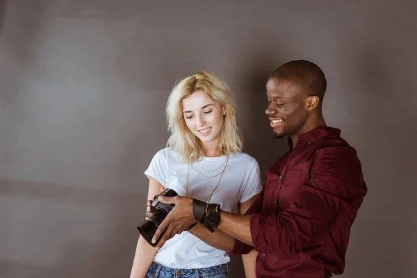 Fotógrafo afro-americano e modelo caucasiano escolhendo fotos juntos durante sessão fotográfica em estúdio — Fotografia de Stock