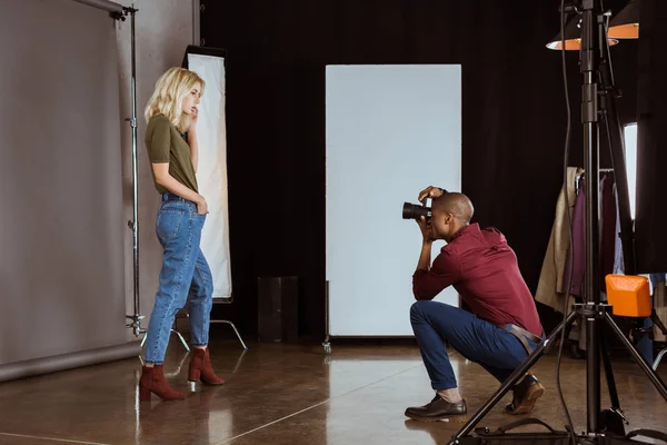 Photographe afro-américain prenant une photo de modèle attrayant en studio — Photo de stock