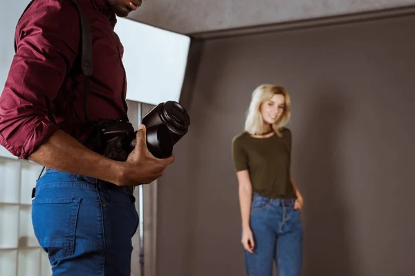 Вибірковий фокус афроамериканського фотографа з фотоапаратом і красивою моделлю в студії — стокове фото