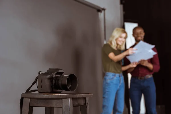 Selective focus of photo camera and african american photographer and model looking at portfolio in studio — Stock Photo