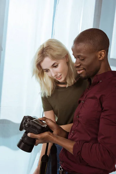 Portrait of african american photographer and caucasian model choosing photos together during photoshoot in studio — Stock Photo