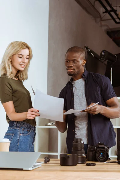 Portrait of multicultural photographers discussing portfolio together at workplace in office — Stock Photo