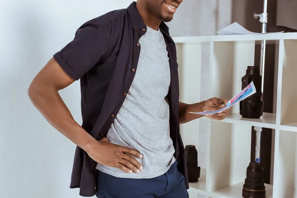 Plan recadré d'un homme afro-américain souriant avec des papiers à la main debout en studio — Photo de stock