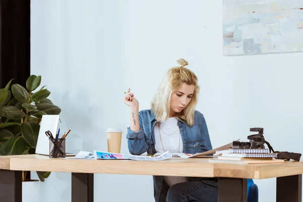 Retrato de fotógrafo atencioso olhando para exemplos de fotos no local de trabalho no escritório — Fotografia de Stock