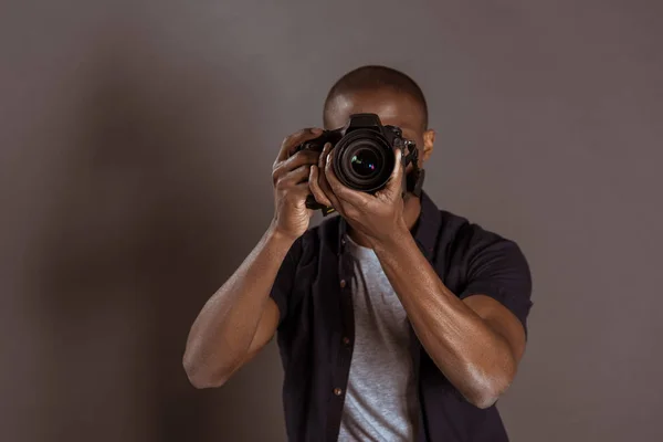 Vista oscurecida del fotógrafo afroamericano tomando fotos en cámara fotográfica - foto de stock
