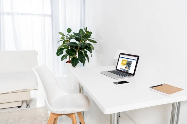 Home office con computer portatile con logo bookingcom, smartphone e notebook sul tavolo — Foto stock