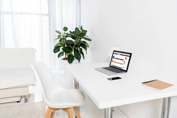 Laptop with soundcloud logo, smartphone and notebook on table in living room — Stock Photo