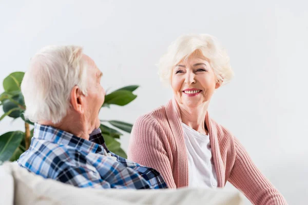 Hermosa pareja de ancianos sentados en el sofá en casa y hablando - foto de stock