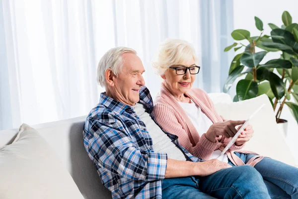Retrato de la esposa y el esposo mayores usando tableta juntos en casa - foto de stock