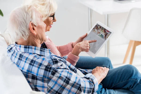 Vista lateral de la pareja de personas mayores utilizando tableta digital con logotipo cuadrado juntos - foto de stock
