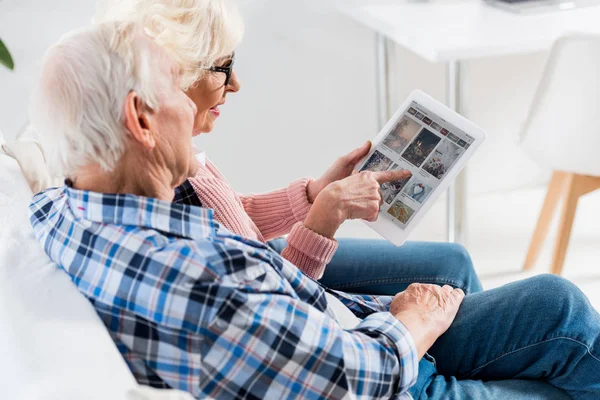 Side view of senior couple using digital tablet with pinterest logo together — Stock Photo